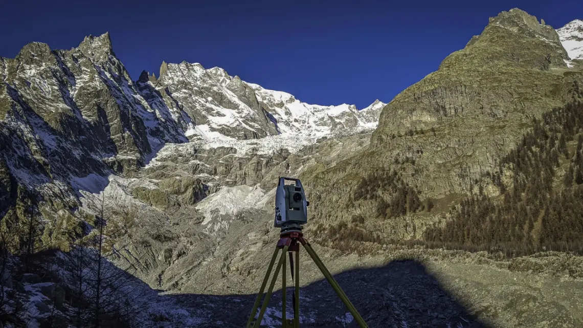 Total station on a tripod in front of a glacier