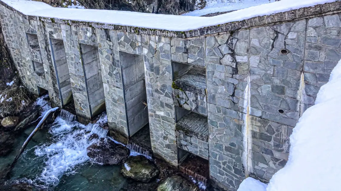 Stone check dam on a snowy mountain stream