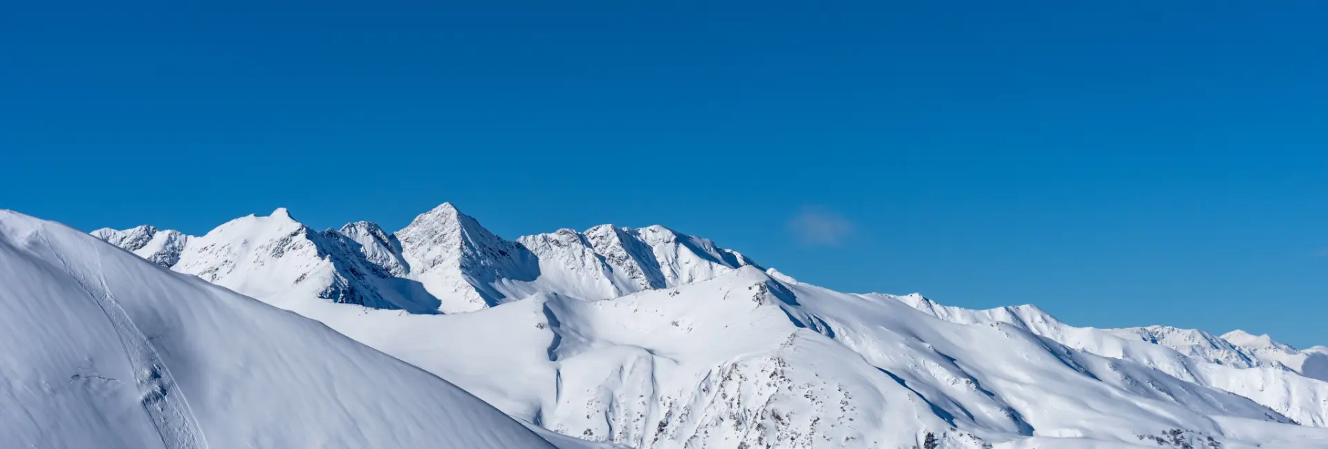 Snow-covered Alpine peaks under a blue sky