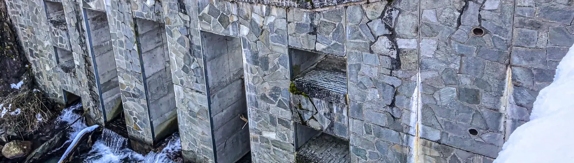 Stone check dam on a snowy mountain stream