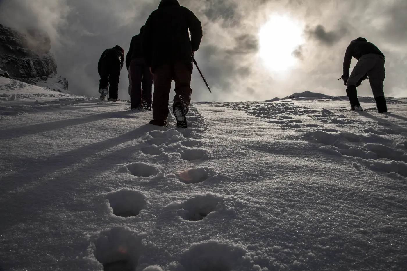 People with poles walking in line on a snowy slope