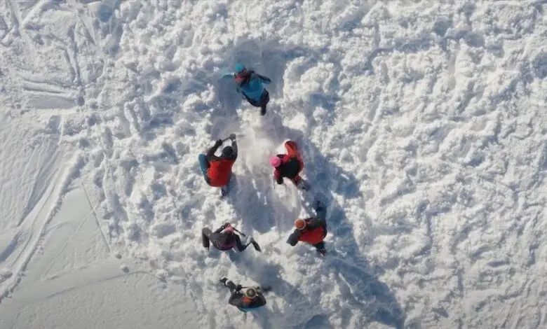 Rescuers in a circle on avalanche debris, seen from above