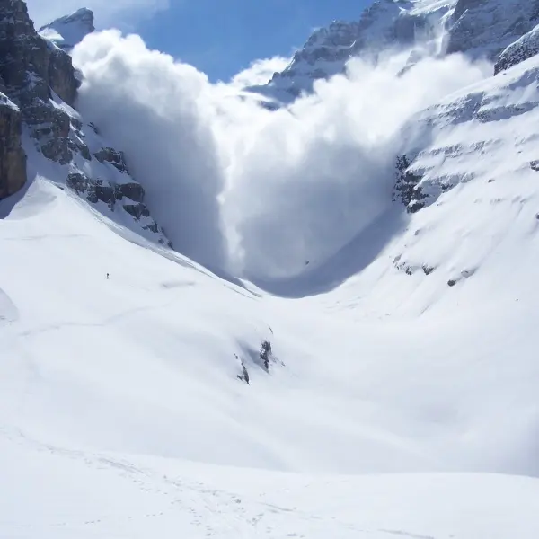 Avalanche breaking off a gully above a hiker