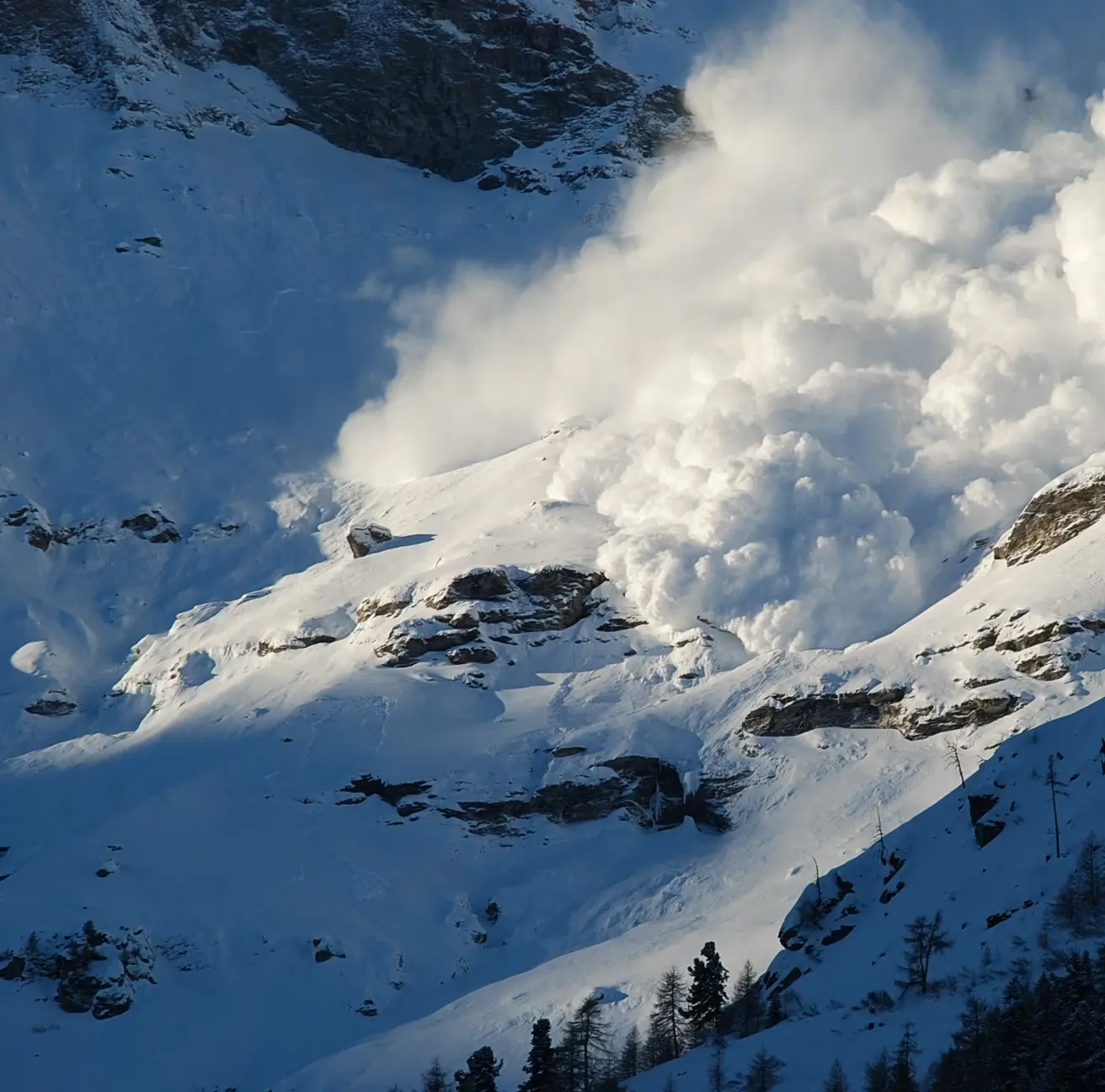 Avalanche running down a steep snowy slope